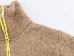 Detail of camel fleece jacket with stand collar, metal zipper and yellow trim edges