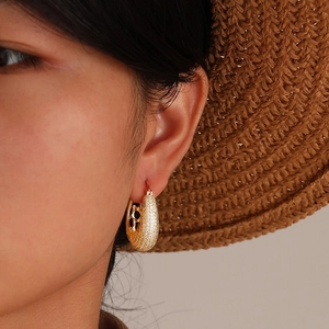 Close-up of a woman wearing gold teardrop earrings inlaid with cubic zirconia
