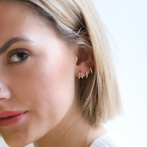 Close-up of gold-plated huggie hoop earrings with colorful zircon stones on model