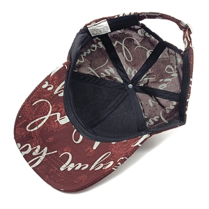 Detail view of burgundy polyester cap with inner lining, metal buckle and care label