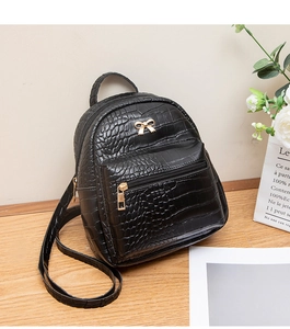 Detail of black faux crocodile leather mini backpack with golden metal bow and zipper