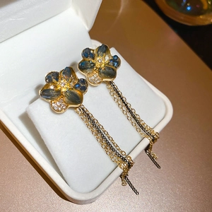 Macro detail of floral tassel earrings with blue gemstones and dangling golden chains