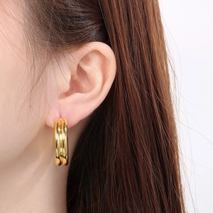 Close-up of minimalist triple-layered gold C-shape hoop earring worn by a model