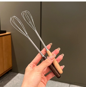Detail of wooden handle whisk being held to show manual cream mixing and size scale