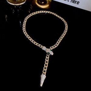 Close-up of gold snake necklace featuring green gemstone eyes and sparkling crystal pavé