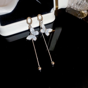Detail view of silver butterfly tassel earrings with crystals on a dark jewelry box