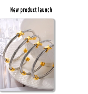 Detail showing cable twist bangle with golden X motif on a white ceramic plate