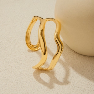 Macro shot of 18K gold plated double-layer wavy open ring on a textured cream surface