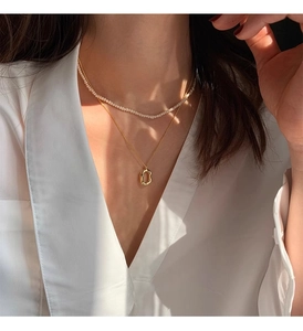 Detail of double-layered 925 silver necklace with pearls and oval pendant on a model