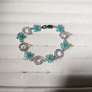 Detail of silver flower bracelet with light blue crystals and pave zircon rings