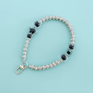Detail view of silver metal keychain with pearls, black star pendant and rhinestones