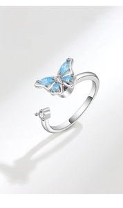 Close-up of rotatable butterfly ring featuring light blue gems and a silver open band