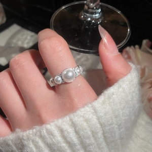 Macro shot of a silver band ring with five gradient pearls and zircons on a model's finger