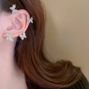 Detailed view of silver butterfly ear cuffs with sparkling crystals on a model's ear