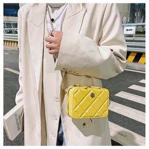 Detail showing a yellow quilted PVC jelly bag with gold chain strap and flower ornament
