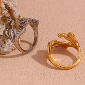 Detailed view of silver and gold plated wavy leaf rings on a natural stone surface