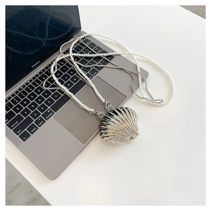 Detail of metallic shell bag with pearl handle and silver chain strap on a laptop