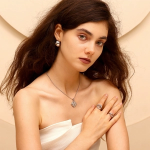 Professional model wearing minimalist silver jewelry set including necklace, earrings and rings