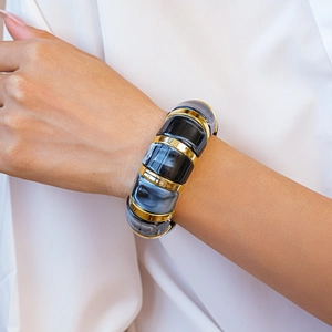 Detail of marble resin and gold metal geometric cuff bracelet worn by a model