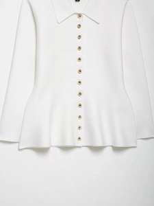 Detail of white knit cardigan showing gold buttons and elegant peplum ruffled hemline