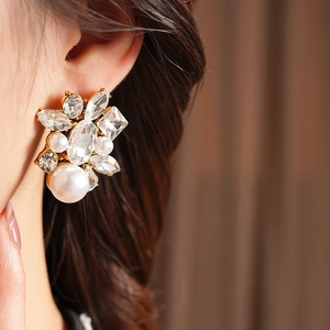 Close-up of model wearing oval pearl drop earrings with rhinestones in retro French style