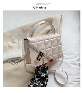Détail du sac matelassé blanc crème avec fermoir rotatif doré et bandoulière chaîne