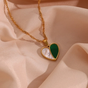 Detailed close-up of heart pendant necklace with green and shell textures on silk