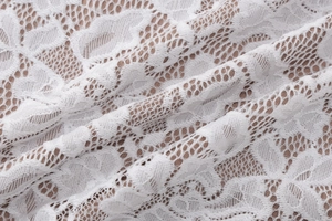 Close-up of white floral lace fabric with intricate mesh patterns on a slim fit maxi dress