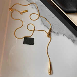 Elegant gold-tone Y-shape snake chain necklace with dual teardrop pendants on marble surface