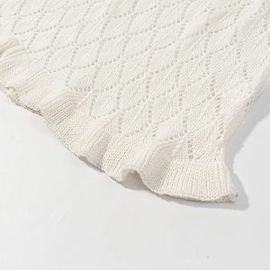 Detail of white V-neck dress featuring delicate diamond hollow knit and wavy scalloped edges