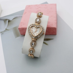 Gros plan sur la montre à quartz dorée en forme de cœur avec ornements en strass brillants