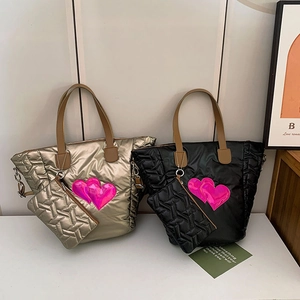 Detail of quilted tote bags in champagne and black with vibrant pink heart patches