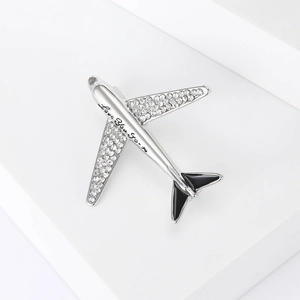 Macro detail of silver airplane brooch featuring Love You Forever engraving and zircons
