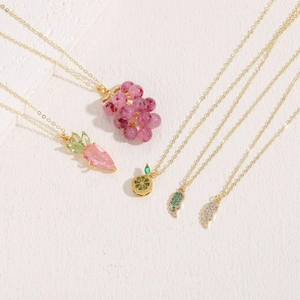 Golden necklace set with colorful zircon fruit and wing pendants on white background