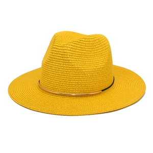 Close-up of bright yellow straw fedora featuring dense weaving and a gold metal decorative band