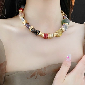 Close-up of vintage ceramic necklace with colorful gemstones on model's collarbone