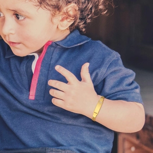 Detailed close-up of custom gold-plated mesh ID bracelet worn by a child on wrist