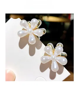 Détail de pinces à cheveux fleur avec perles blanches et accents métalliques dorés