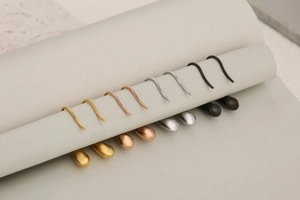 Detailed close-up of teardrop hook earrings in gold, rose gold, silver, and black finish