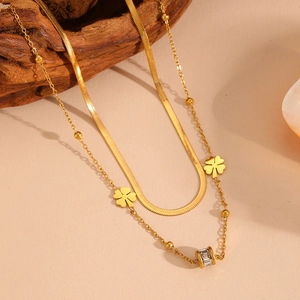 Close-up of gold double-layer necklace with clover charms and polished snake chain detail
