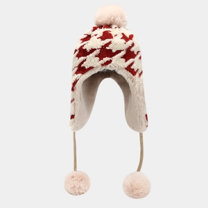 Winter knitted trapper hat for women with red houndstooth pattern and soft faux fur pom-poms