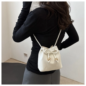 Dettaglio della borsa a secchiello bianca intrecciata con perle dorate indossata