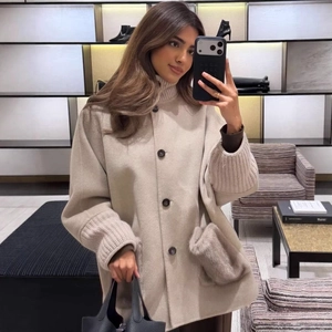 Beige mid-length wool coat with knit cuffs and faux fur pockets in a boutique setting