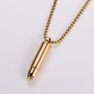 Macro shot of gold bullet pendant with polished finish and detailed bead chain