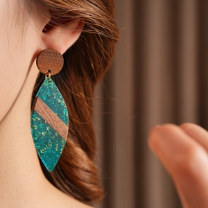 Détail de boucles d'oreilles en bois avec résine sarcelle et feuilles d'or