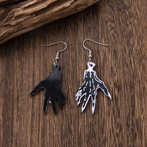 Detail shot of gothic ghost hand acrylic earrings on rustic wood background