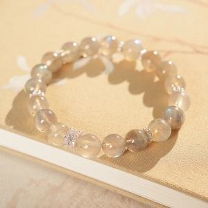 Detailed shot of natural moonstone beads bracelet with a zircon-inlaid barrel charm