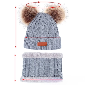 Détail du bonnet et du tour de cou gris en maille torsadée avec pompons en fourrure