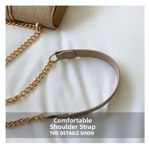 Detail van beige tas met krokodillenpatroon, gouden ketting en leren schouderband