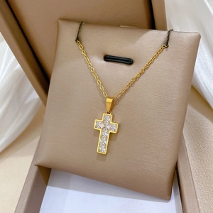 Close-up of a gold cross necklace with square zircons on a luxury jewelry display pillow